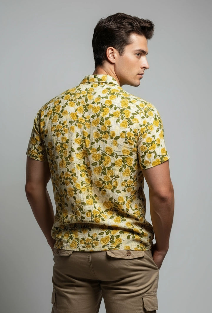 Man wearing a yellow floral shirt and brown pants on a gray background
