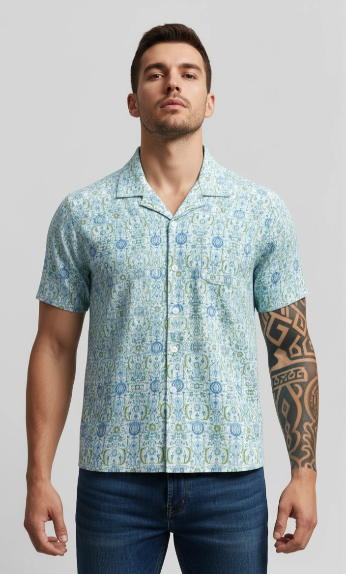 Man wearing a patterned short-sleeve shirt against a plain background